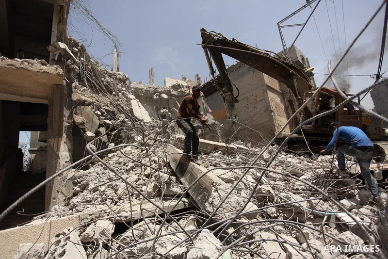 Palestinian men work on the remains of a building destroyed during the recent Israeli war 2014, in Shijaiyah neighborhood in the east of Gaza city, on April 30, 2016. Israel’s punitive ban on cement imports into the Gaza...