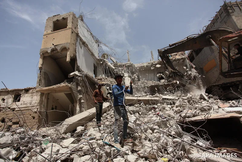 Palestinian men work on the remains of a building destroyed during the recent Israeli war 2014, in Shijaiyah neighborhood in the east of Gaza city, on April 30, 2016. Israel’s punitive ban on cement imports into the Gaza...