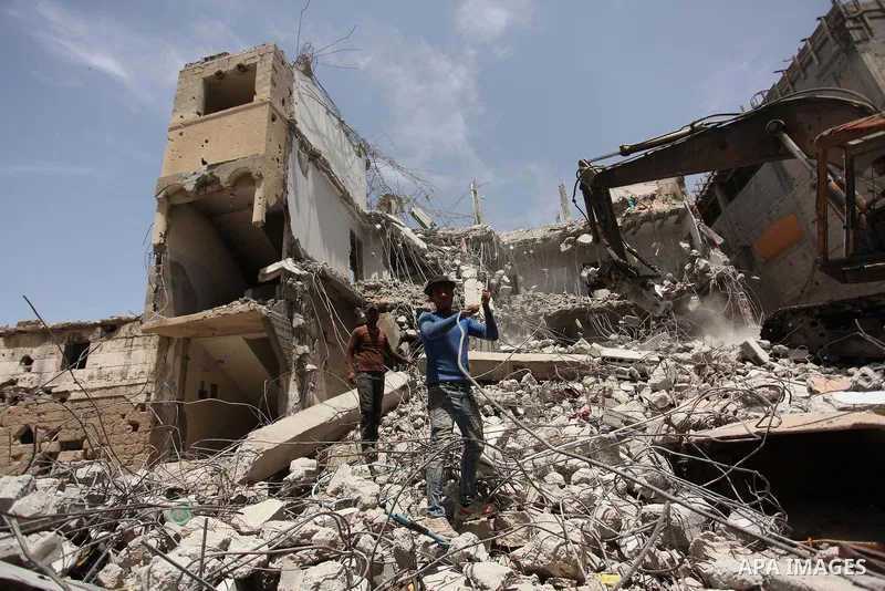 Palestinian men work on the remains of a building destroyed during the recent Israeli war 2014, in Shijaiyah neighborhood in the east of Gaza city, on April 30, 2016. Israel’s punitive ban on cement imports into the Gaza...
