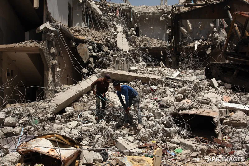 Palestinian men work on the remains of a building destroyed during the recent Israeli war 2014, in Shijaiyah neighborhood in the east of Gaza city, on April 30, 2016. Israel’s punitive ban on cement imports into the Gaza...