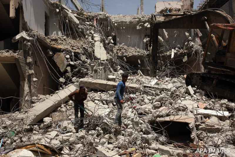 Palestinian men work on the remains of a building destroyed during the recent Israeli war 2014, in Shijaiyah neighborhood in the east of Gaza city, on April 30, 2016. Israel’s punitive ban on cement imports into the Gaza...