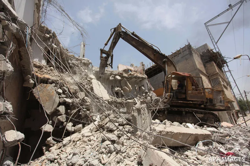 Palestinian men work on the remains of a building destroyed during the recent Israeli war 2014, in Shijaiyah neighborhood in the east of Gaza city, on April 30, 2016. Israel’s punitive ban on cement imports into the Gaza...