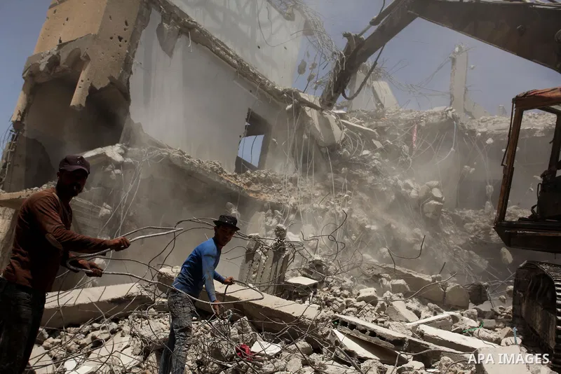 Palestinian men work on the remains of a building destroyed during the recent Israeli war 2014, in Shijaiyah neighborhood in the east of Gaza city, on April 30, 2016. Israel’s punitive ban on cement imports into the Gaza...