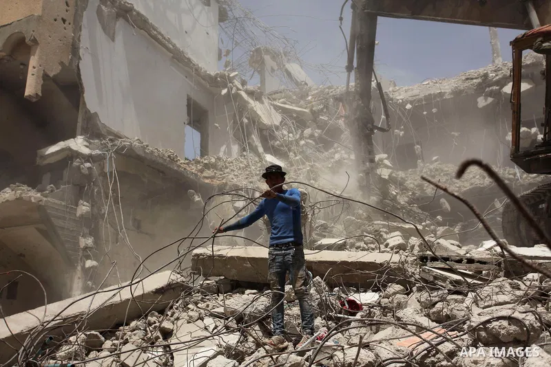 Palestinian men work on the remains of a building destroyed during the recent Israeli war 2014, in Shijaiyah neighborhood in the east of Gaza city, on April 30, 2016. Israel’s punitive ban on cement imports into the Gaza...
