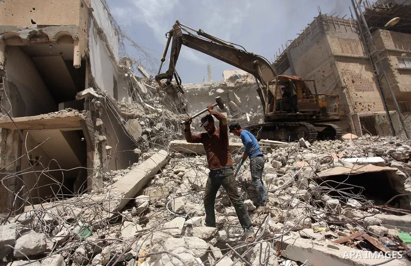 Palestinian men work on the remains of a building destroyed during the recent Israeli war 2014, in Shijaiyah neighborhood in the east of Gaza city, on April 30, 2016. Israel’s punitive ban on cement imports into the Gaza...