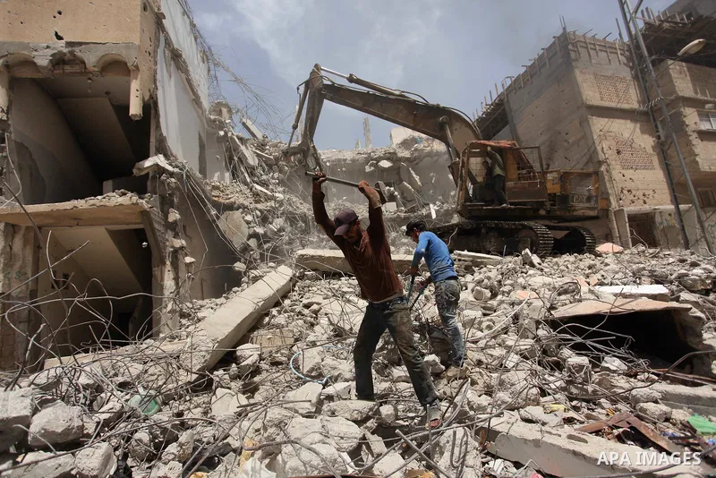 Palestinian men work on the remains of a building destroyed during the recent Israeli war 2014, in Shijaiyah neighborhood in the east of Gaza city, on April 30, 2016. Israel’s punitive ban on cement imports into the Gaza...