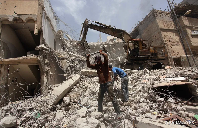 Palestinian men work on the remains of a building destroyed during the recent Israeli war 2014, in Shijaiyah neighborhood in the east of Gaza city, on April 30, 2016. Israel’s punitive ban on cement imports into the Gaza...