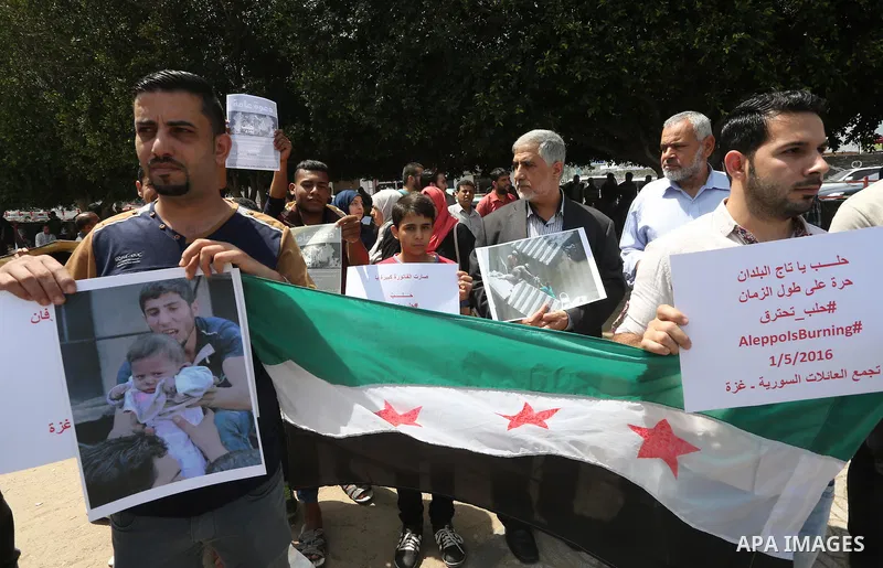 Syrians who live in the Gaza Strip after fleeing their war-hit country hold placards during a rally against Syrian government shelling on the northern city of Aleppo, on May 1, 2016, in Gaza City. Photo by Mohammed Asad