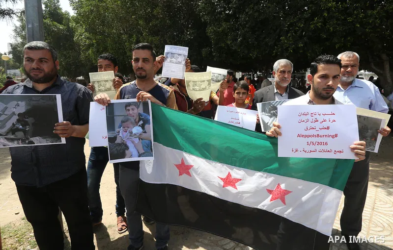 Syrians who live in the Gaza Strip after fleeing their war-hit country hold placards during a rally against Syrian government shelling on the northern city of Aleppo, on May 1, 2016, in Gaza City. Photo by Mohammed Asad