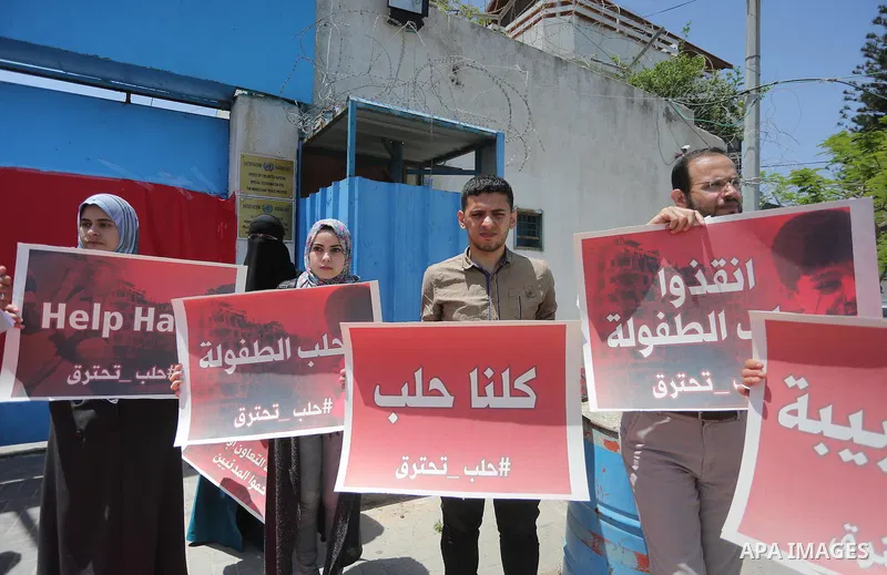 Palestinians hold placards during a rally against Syrian government shelling on the northern city of Aleppo, in front of the headquarter United Nation "UNSCO" in Gaza City, on May 2, 2016. Photo by Mohammed Asad