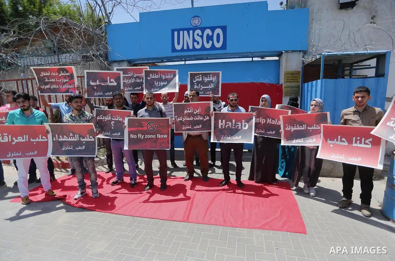 Palestinians hold placards during a rally against Syrian government shelling on the northern city of Aleppo, in front of the headquarter United Nation "UNSCO" in Gaza City, on May 2, 2016. Photo by Mohammed Asad