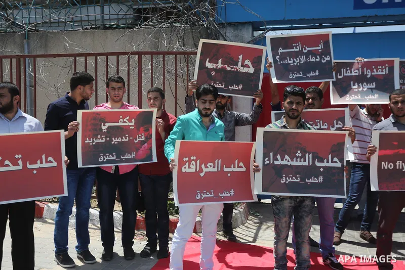 Palestinians hold placards during a rally against Syrian government shelling on the northern city of Aleppo, in front of the headquarter United Nation "UNSCO" in Gaza City, on May 2, 2016. Photo by Mohammed Asad