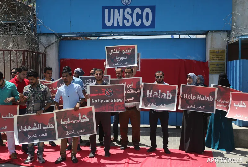Palestinians hold placards during a rally against Syrian government shelling on the northern city of Aleppo, in front of the headquarter United Nation "UNSCO" in Gaza City, on May 2, 2016. Photo by Mohammed Asad