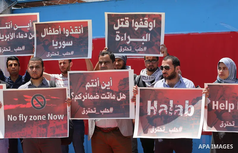 Palestinians hold placards during a rally against Syrian government shelling on the northern city of Aleppo, in front of the headquarter United Nation "UNSCO" in Gaza City, on May 2, 2016. Photo by Mohammed Asad