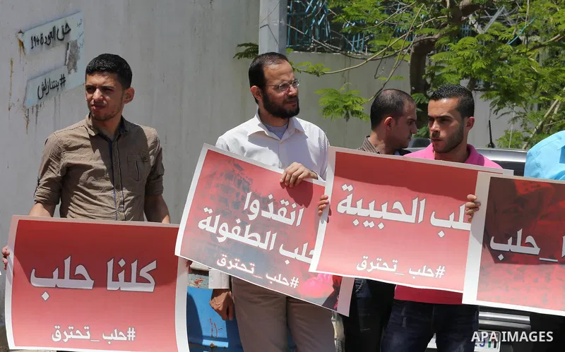 Palestinians hold placards during a rally against Syrian government shelling on the northern city of Aleppo, in front of the headquarter United Nation "UNSCO" in Gaza City, on May 2, 2016. Photo by Mohammed Asad