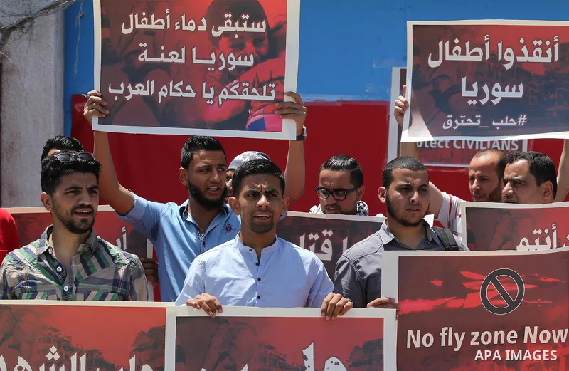 Palestinians hold placards during a rally against Syrian government shelling on the northern city of Aleppo, in front of the headquarter United Nation "UNSCO" in Gaza City, on May 2, 2016. Photo by Mohammed Asad