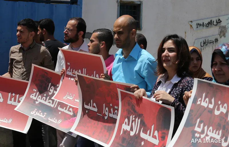 Palestinians hold placards during a rally against Syrian government shelling on the northern city of Aleppo, in front of the headquarter United Nation "UNSCO" in Gaza City, on May 2, 2016. Photo by Mohammed Asad