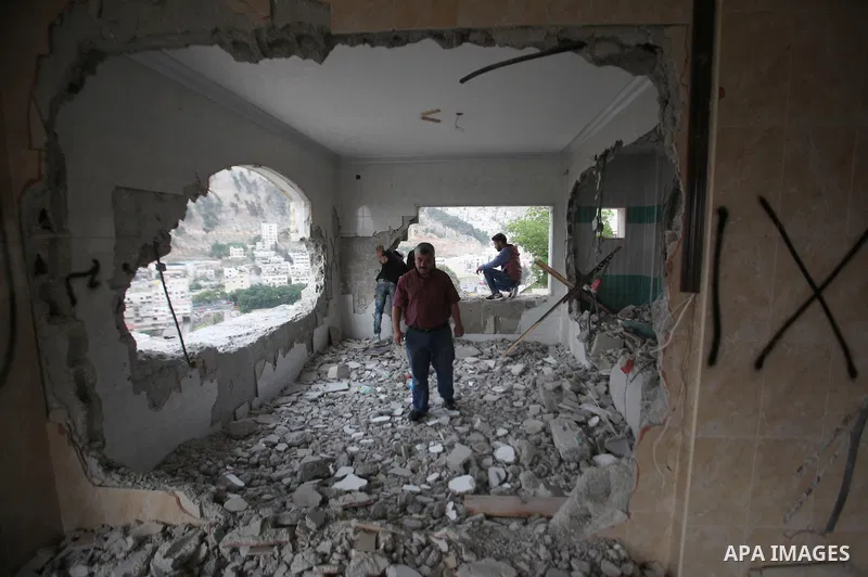 Palestinians look at the damage in the West Bank city of Nablus on May 3, 2016, after Israeli forces destroyed the house of Zaid Amer, a Palestinian man accused of taking part in the killing of a Jewish settler couple ne...
