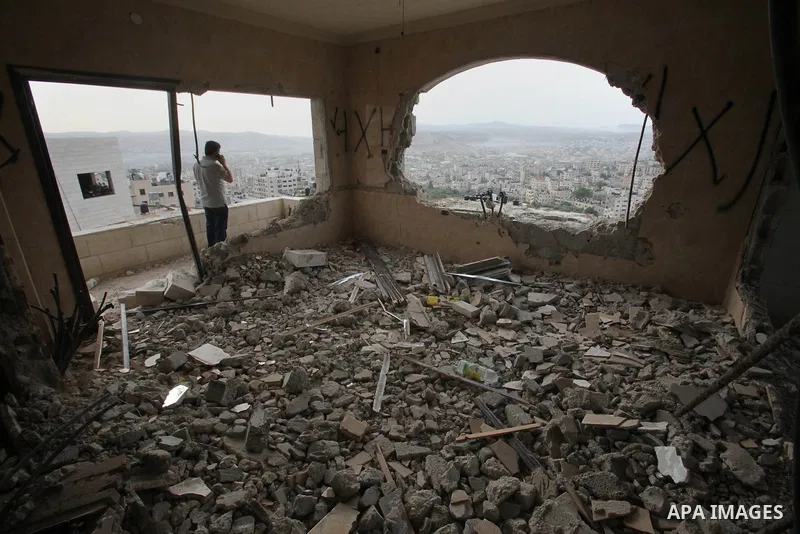 Palestinians look at the damage in the West Bank city of Nablus on May 3, 2016, after Israeli forces destroyed the house of Zaid Amer, a Palestinian man accused of taking part in the killing of a Jewish settler couple ne...