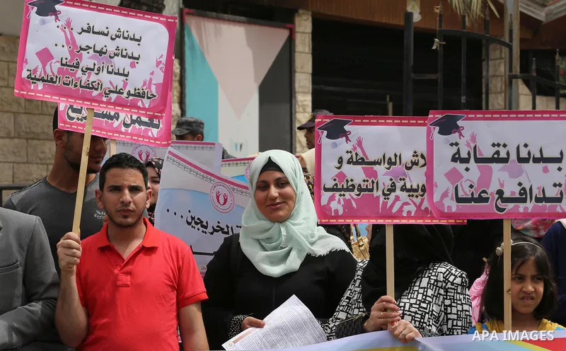 Palestinian graduates hold banners during a protest to demand jobs, in front of the Council of Ministers, in Gaza City, on May 3, 2016. Photo by Mohammed Asad