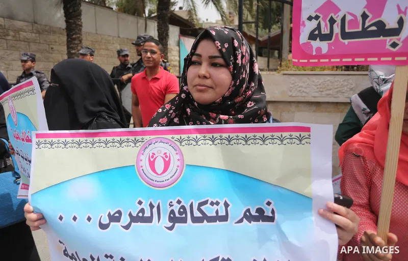 Palestinian graduates hold banners during a protest to demand jobs, in front of the Council of Ministers, in Gaza City, on May 3, 2016. Photo by Mohammed Asad