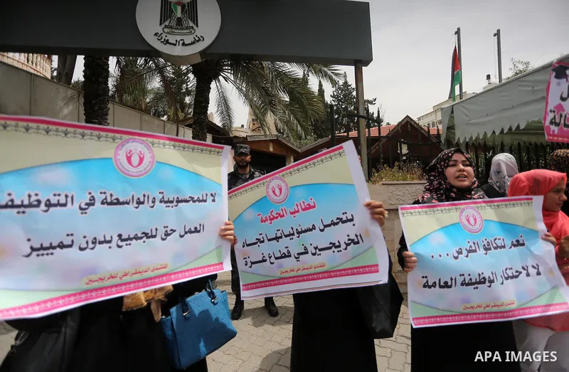 Palestinian graduates hold banners during a protest to demand jobs, in front of the Council of Ministers, in Gaza City, on May 3, 2016. Photo by Mohammed Asad