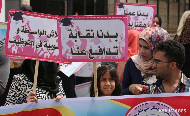 Palestinian graduates hold banners during a protest to demand jobs, in front of the Council of Ministers, in Gaza City, on May 3, 2016. Photo by Mohammed Asad
