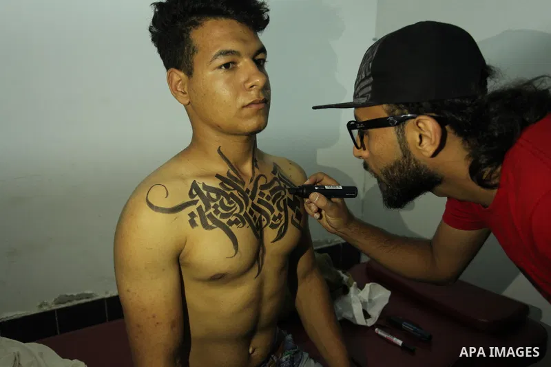 A Palestinian artist Bilal Khalid paints Arabic letters on a bodybuilder body at a gym in Khan Younis in the southern Gaza strip, on May 3, 2016. Photo by Ashraf Amra