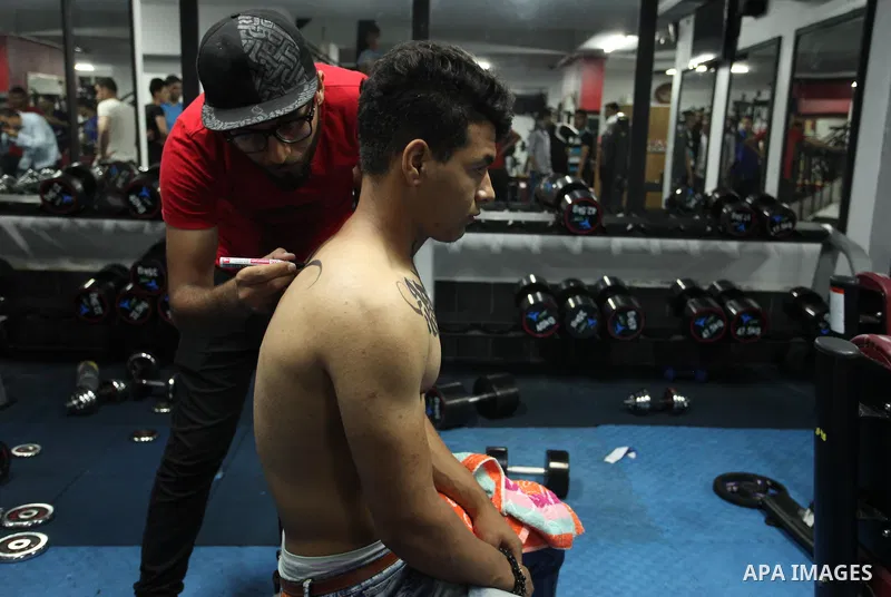 A Palestinian artist Bilal Khalid paints Arabic letters on a bodybuilder body at a gym in Khan Younis in the southern Gaza strip, on May 3, 2016. Photo by Ashraf Amra