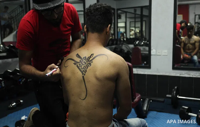 A Palestinian artist Bilal Khalid paints Arabic letters on a bodybuilder body at a gym in Khan Younis in the southern Gaza strip, on May 3, 2016. Photo by Ashraf Amra
