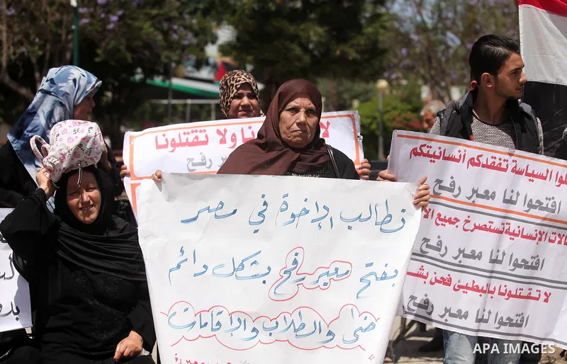 Palestinians hold banners during a protest demanding the Egyptian authorities for the opening of the Rafah crossing, in Gaza, on May 4, 2016. Photo by Ashraf Amra