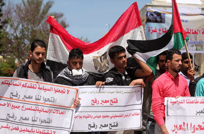 Palestinians hold banners during a protest demanding the Egyptian authorities for the opening of the Rafah crossing, in Gaza, on May 4, 2016. Photo by Ashraf Amra