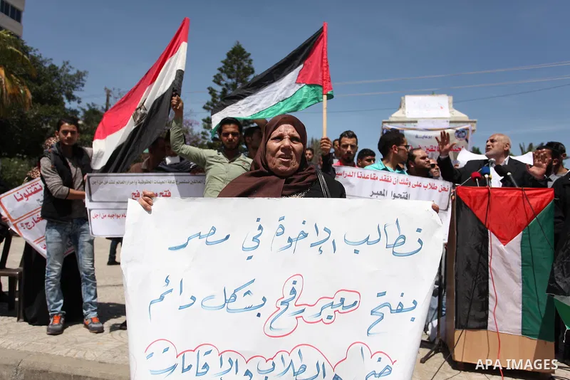 Palestinians hold banners during a protest demanding the Egyptian authorities for the opening of the Rafah crossing, in Gaza, on May 4, 2016. Photo by Ashraf Amra