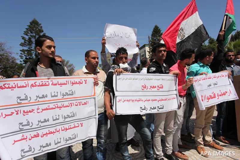 Palestinians hold banners during a protest demanding the Egyptian authorities for the opening of the Rafah crossing, in Gaza, on May 4, 2016. Photo by Ashraf Amra