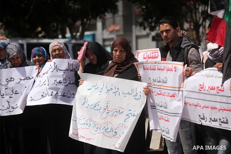 Palestinians hold banners during a protest demanding the Egyptian authorities for the opening of the Rafah crossing, in Gaza, on May 4, 2016. Photo by Ashraf Amra