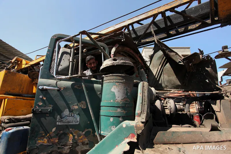 A Palestinian man inspects a damaged vehicle at his workshop after it was hit by an Israeli air strike in Gaza City, in the early hours of May 5, 2016. Israeli air strikes hit four Hamas sites in Gaza overnight, the mili...
