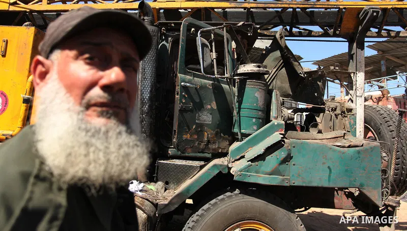 A Palestinian man inspects a damaged vehicle at his workshop after it was hit by an Israeli air strike in Gaza City, in the early hours of May 5, 2016. Israeli air strikes hit four Hamas sites in Gaza overnight, the mili...