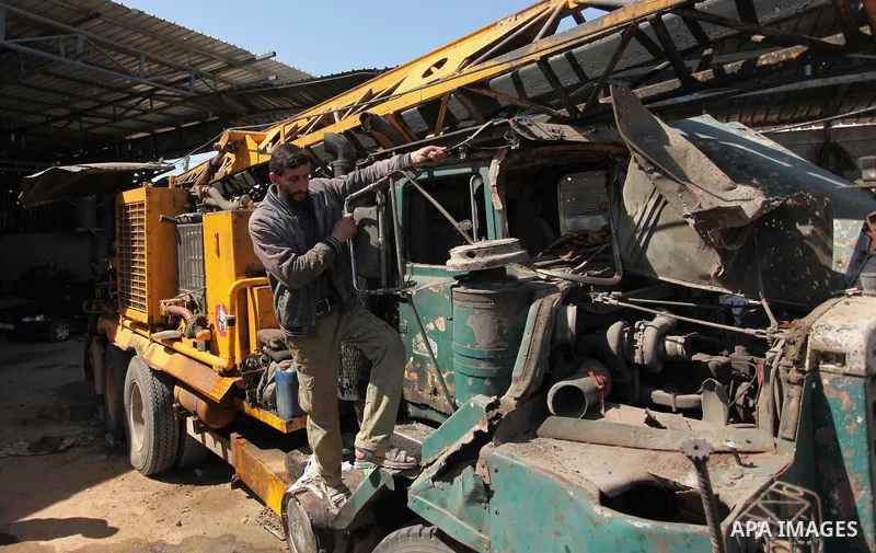 A Palestinian man inspects a damaged vehicle at his workshop after it was hit by an Israeli air strike in Gaza City, in the early hours of May 5, 2016. Israeli air strikes hit four Hamas sites in Gaza overnight, the mili...