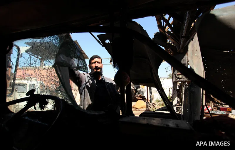 A Palestinian man inspects a damaged vehicle at his workshop after it was hit by an Israeli air strike in Gaza City, in the early hours of May 5, 2016. Israeli air strikes hit four Hamas sites in Gaza overnight, the mili...