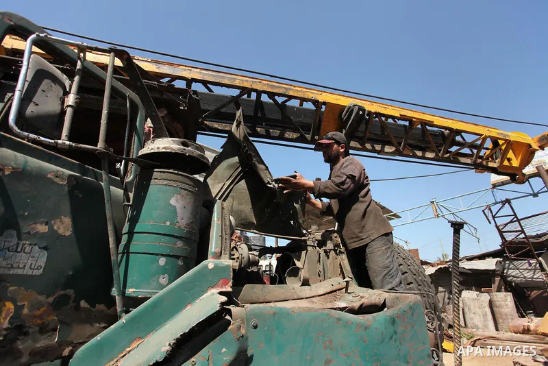 A Palestinian man inspects a damaged vehicle at his workshop after it was hit by an Israeli air strike in Gaza City, in the early hours of May 5, 2016. Israeli air strikes hit four Hamas sites in Gaza overnight, the mili...