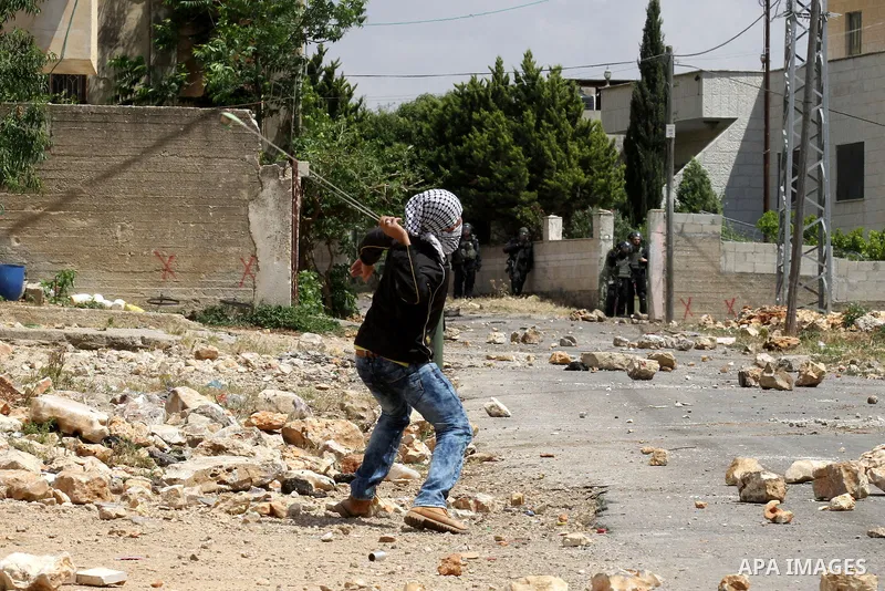 A Palestinian protester uses a slingshot to hurl stones towards Israeli security forces during clashes following a demonstration against the expropriation of Palestinian land by Israel on May 06, 2016 in the village of K...