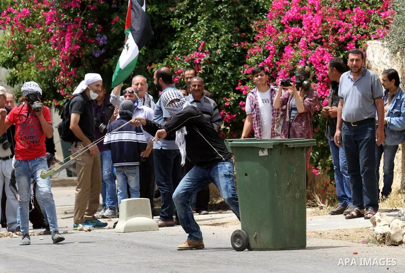 A Palestinian protester uses a slingshot to hurl stones towards Israeli security forces during clashes following a demonstration against the expropriation of Palestinian land by Israel on May 06, 2016 in the village of K...