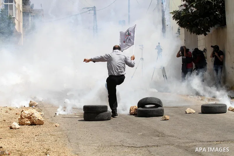 A Palestinian protester kicks back a tear gas canister fired by Israeli security forces during clashes following a demonstration against the expropriation of Palestinian land by Israel on May 06, 2016 in the village of K...