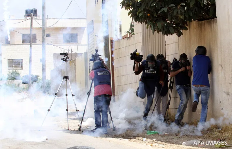 Cameramen takes cover from a tear gas canister fired by Israeli security forces during clashes following a demonstration against the expropriation of Palestinian land by Israel on May 06, 2016 in the village of Kfar Qadd...