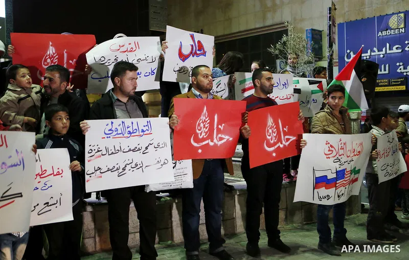 Palestinian hold placards during a protest to show solidarity with Syria in the West Bank of Hebron on May 06, 2016. Photo by Wisam Hashlamoun