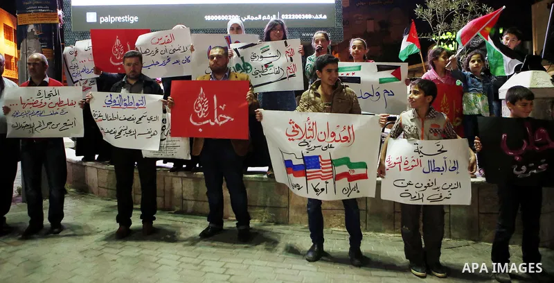 Palestinian hold placards during a protest to show solidarity with Syria in the West Bank of Hebron on May 06, 2016. Photo by Wisam Hashlamoun