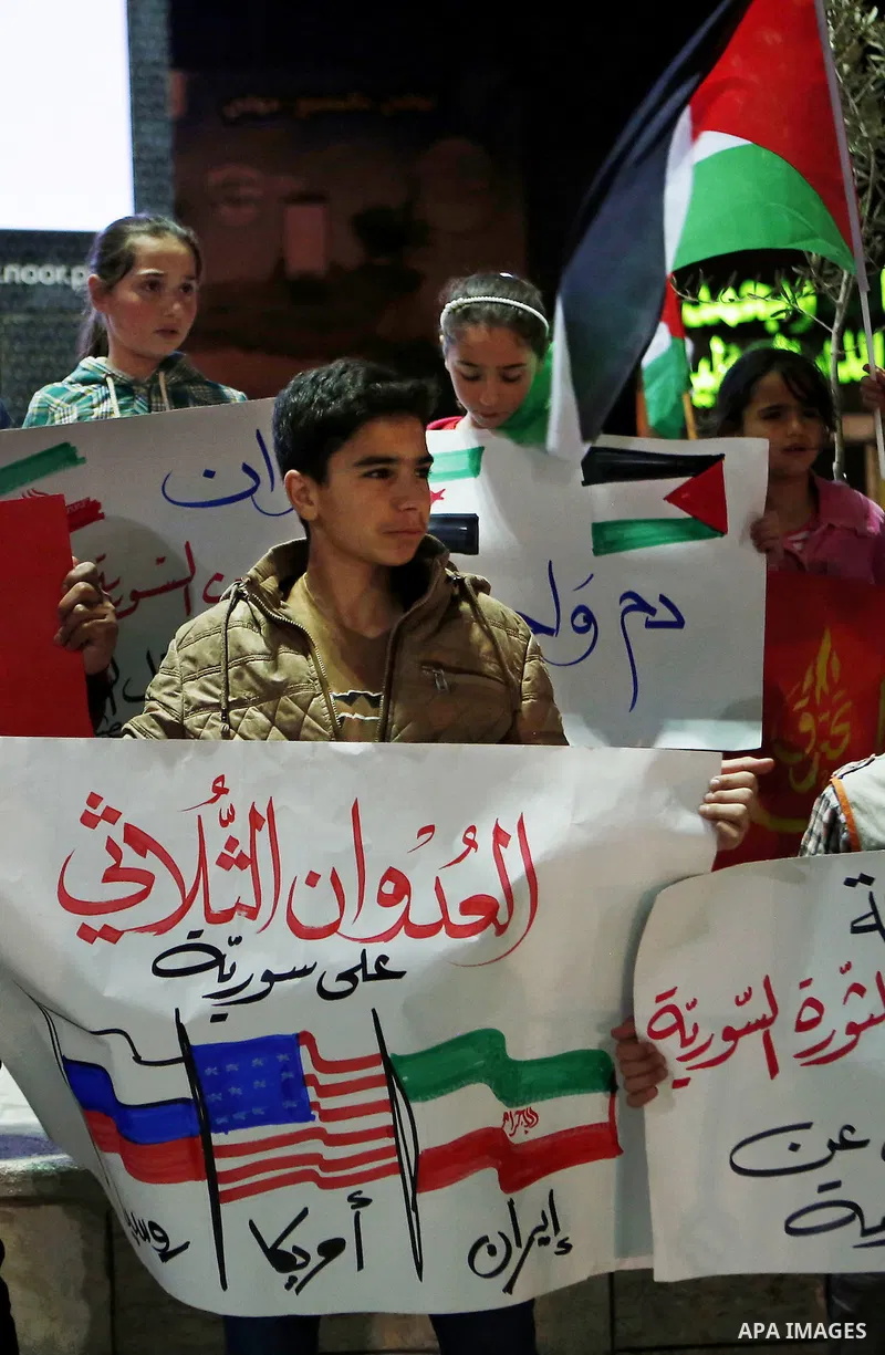 Palestinian hold placards during a protest to show solidarity with Syria in the West Bank of Hebron on May 06, 2016. Photo by Wisam Hashlamoun