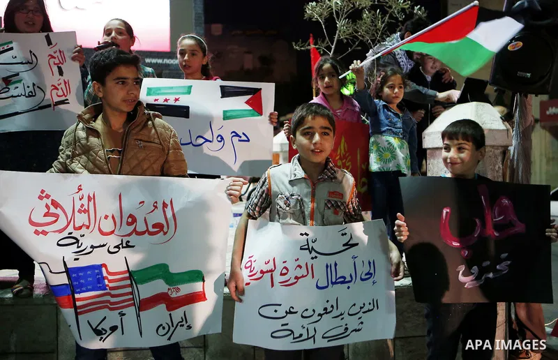 Palestinian hold placards during a protest to show solidarity with Syria in the West Bank of Hebron on May 06, 2016. Photo by Wisam Hashlamoun