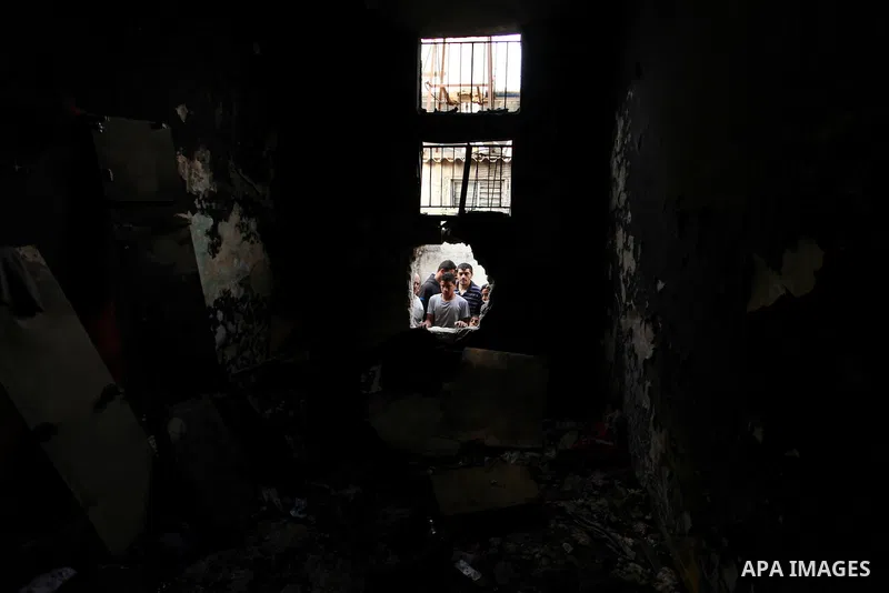 Palestinians look through the window of burnt house after a candle caused a fire at the al-Hendi family's home at the al-Shati refugee camp in Gaza City on May 7, 2016. Photo by Ashraf Amra
