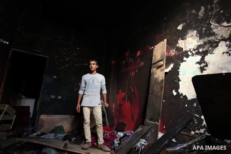 A Palestinian man looks at the charred walls of a house after a candle caused a fire at the al-Hendi family's home at the al-Shati refugee camp in Gaza City on May 7, 2016. Photo by Ashraf Amra